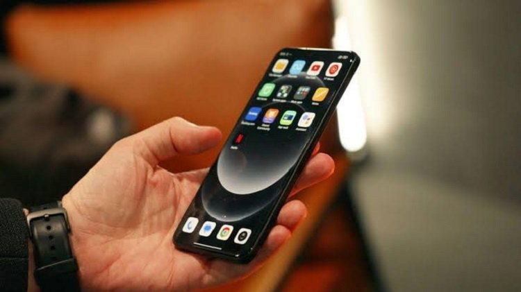 گوشی آیفون در دست کاربر با صفحه اصلی iOS